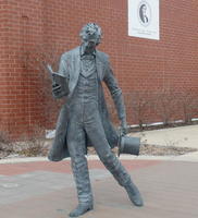 Statue of Lincoln, standing, with stovepipe hat in left hand and book in right hand