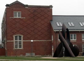 Abstract sculpture in front of building with diamond pattern in brickworks