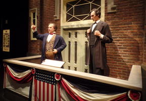 Lincoln and Douglas debating on a platform with bunting on front