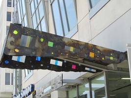 Trapezoidal metal overhang with colored “windows”