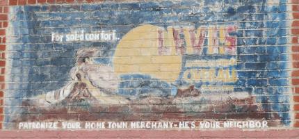 Levis ad painted on brick wall; text: “For solid comfort Levis Amerca's finest overall / patronize your home town merchant - he's your neighbor”