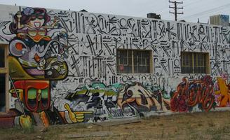 Wall of building painted with cartoonish woman and elephant; letter-like symbols in background