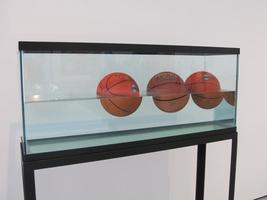 Three basketballs floating in an aquarium tank.