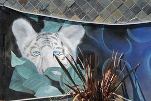 Mural: head of white tiger hiding behind plants