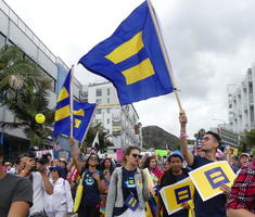 Marchers from Human Rights Campaign carrying flag with yellow equal sign on blue background