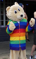 Person in bear costume with rainbow striped jacket