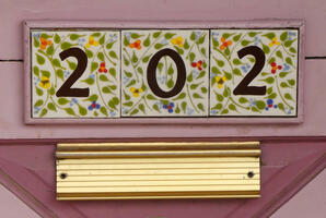 Tiles on a street address painted with flowers and leaves