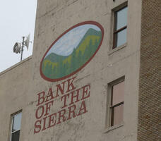 Side of building with painting of a mountainscape and words BANK OF THE SIERRA