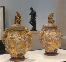 Ornate vases with gold trim and seated figures on lid