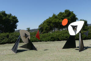 Abstract sculpture in two parts; left part has a triangle on a rod, right part has a circle on a rod.