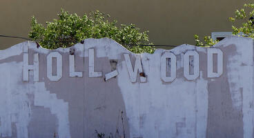Wall with word HOLLYWOOD attached to it in imitation of the Hollywood sign; some letters are falling off.