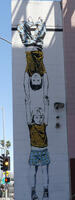 Wall painting of boy hanging by his knees from a wall, holding a girl by her hands.