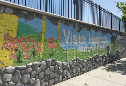 Mosaic sign for Vista Hermosa Natural Park with flowers and irregular stone base