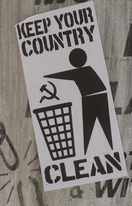 Silhouette of man throwing hammer and sickle in garbage can. Text: keep your country clean
