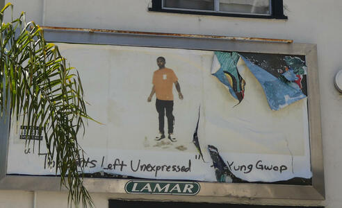 Advert showing a young black man in t-shirt and jeans; for music album “Thoughts Left Unexpressed” by Yung Gwop