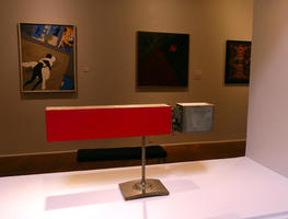Rectangular metal sculpture; red on one end and gray on the other
