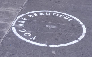 Spray-painted circle with stenciled text: YOU ARE BEAUTIFUL