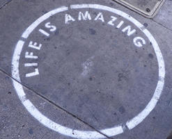 Spray-painted circle with stenciled text: LIFE IS AMAZING