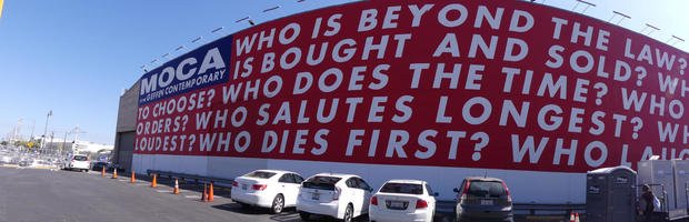Wall-sized art by Barbara Kruger with questions: Who is beyond the law? Who is bought and sold? Who does the time? Who dies first? Who laughs last?