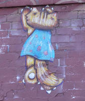 Back view of cat in blue dress scratching at wall