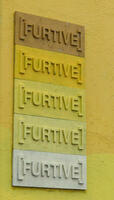 Word [FURTIVE] in bas-relief repeated five times in varying shades of yellow/bown