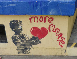 Boy in “Oliver” holding out his hands with a heart in them, and spray-painted words “More Please”