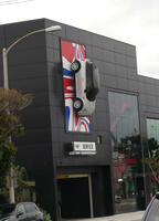 Mini Cooper dealership with life-size car hung vertically on front of building
