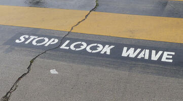 Stenciled letters at intersection: STOP LOOK WAVE