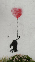 Wall art of black cat with tail attached to string, being lifted in air by heart-shaped balloon