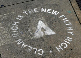 Stenciled letters on sidewalk: CLEAN RICH IS THE NEW FILTHY RICH.