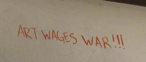 Graffiti “Art Wages War!!!” on back of a metro car seat