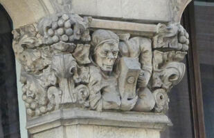 Relief of man holding book surrounded by bowls of grapes