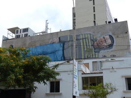Large painting of standing man, painted horizontally on second floor of a buildling.
