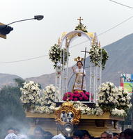 Ornate statue with floral display being carried in a procession.