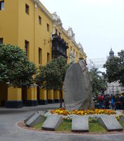 Stone sculpture in foreground; yellow building in background