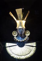 Gold headdress, silver ear rings, necklace, and chest plate.