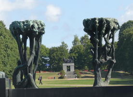 Two tree/people sculptures at either side, arch with figures on roof in center background