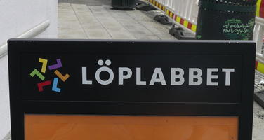 Sign with colored letter Ls in a circle and company name Löplabbet
