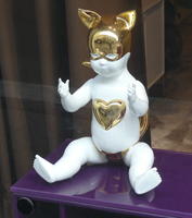 White seated cherub with gold batman-like cowl and heart on chest