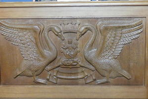 Wooden carving of heraldic crest with swan on either side