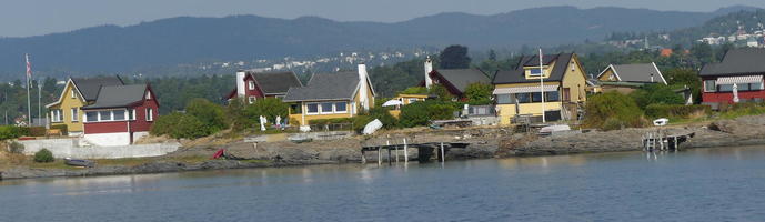 Small yellow and red houses along fjord coast