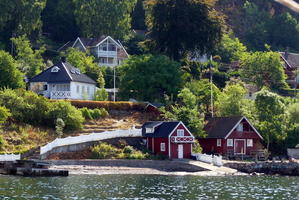Red and white summer houses on coast of fjord