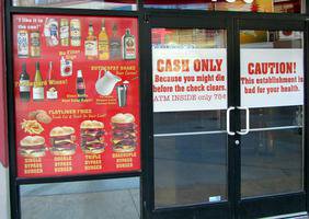 Signs on front of Heart Attack Grill: “Cash only/ Because you might die before the check clears” and “Caution! This establishment is bad for your health.”
