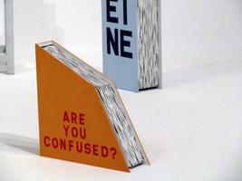 Book cut in half on an angle; cover reads “ARE YOU CONFUSED?”