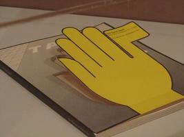 Book cover with yellow hand as paper cutout, folded up from the cover. Thumb is a taxi flag