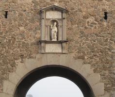 Statue of a bishop in a niche above an arch in a brick wall