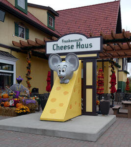 large wedge of cheese with mouse head peeping out