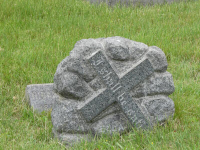 Rock with cross at 45 degree angle; visible text on cross reads “I shall be sati”