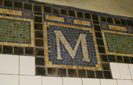 Mosaic with white letter M on blue background