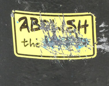 Sticker reading “Abolish the” with remaining word(s) scratched away